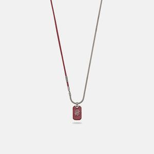 Pendant necklace in burgundy leather and silver on plain stage.