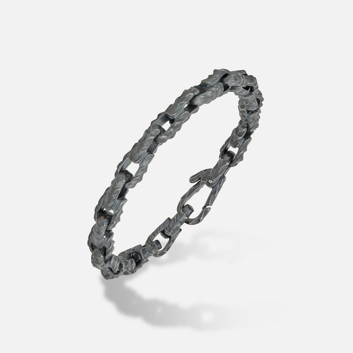 Handcrafted link in distressed metal and dark finish on a minimalist floor.
