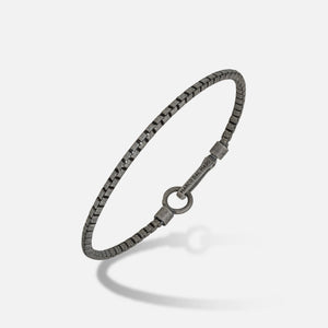 Square chain in burnished metal and logo clasp on a gradient ground.