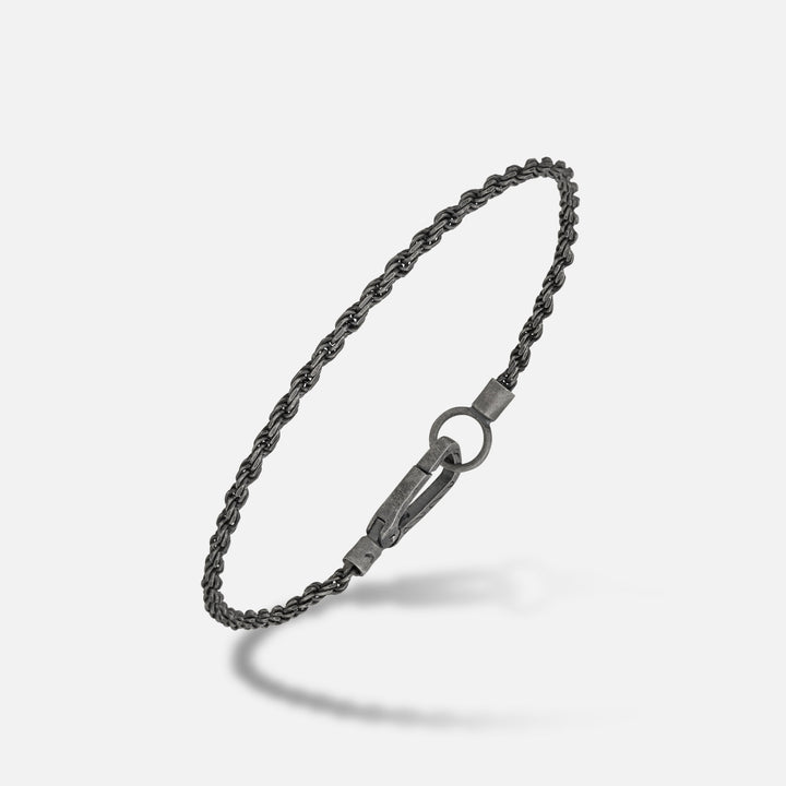 Twisted chain in dark silver and iron finish on a soft shadow floor.
