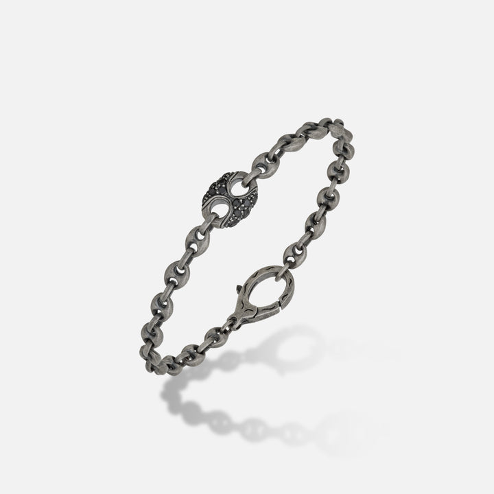 Link chain in oxidized silver and dark gems on a clear base.