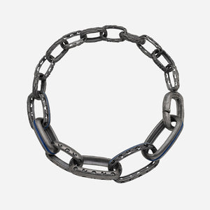 Textured link bracelet in antiqued silver and dark blue enamel positioned on a seamless bright canvas.