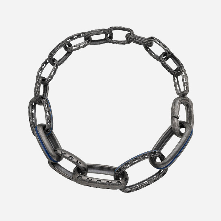 Textured link bracelet in antiqued silver and dark blue enamel positioned on a seamless bright canvas.