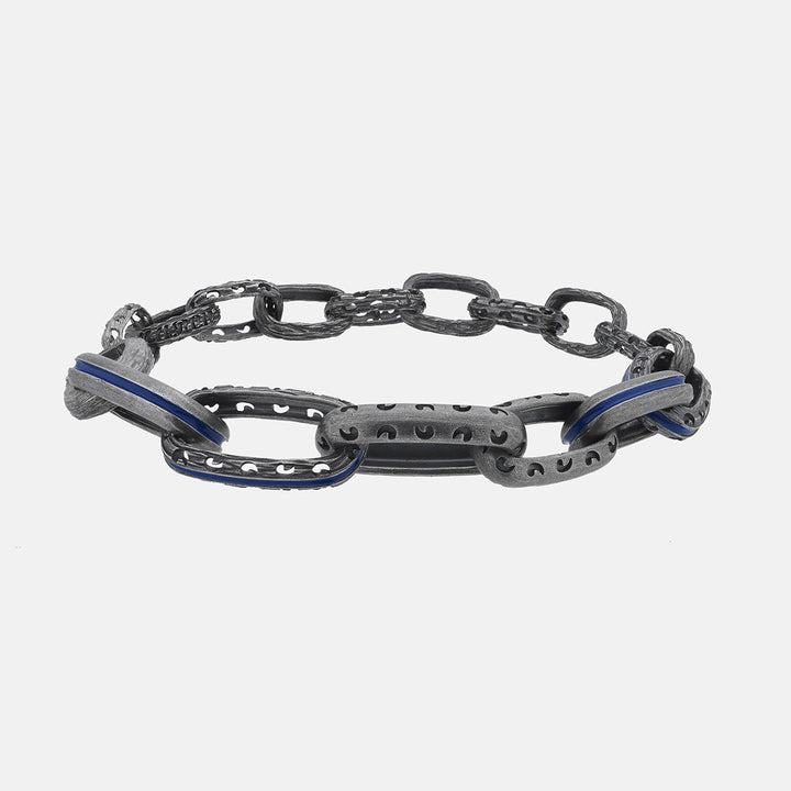 Ground-level view of chain bracelet emphasizing carved dark silver links and deep blue enamel inlays.