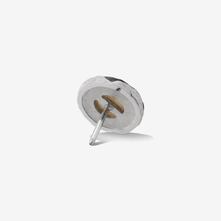 Stud earring in sterling silver and steel on a light studio surface.