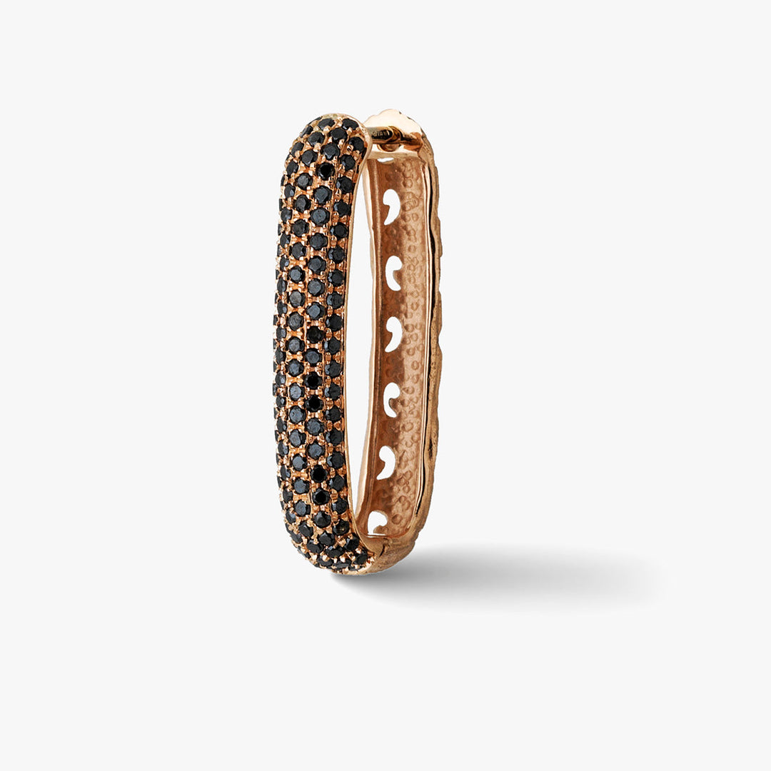 Rectangular hoop earring in carved rose gold and black pavé stones standing on a soft white surface.