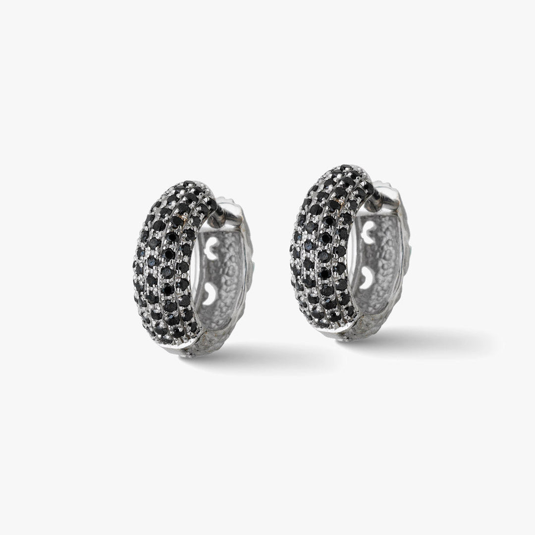 Paired view of crystal earrings displaying dual setting on clean floor.