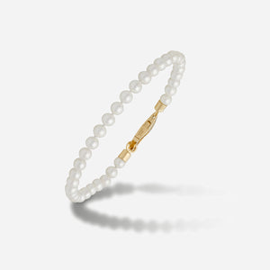 Close-up of a white pearl bracelet and its gold-tone clasp.