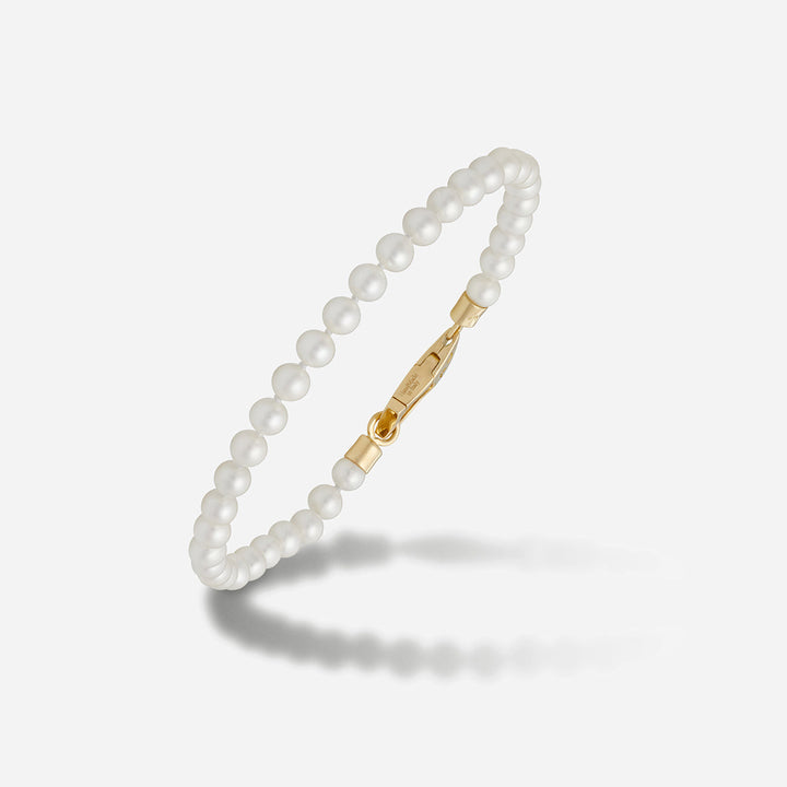 Close-up of a white pearl bracelet and its gold-tone clasp.