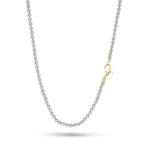 Beaded necklace in light grey stones and off-center yellow gold fastening positioned on a clean white surface.