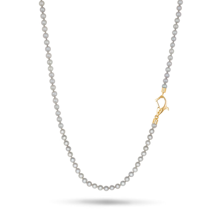 Beaded necklace in light grey stones and off-center yellow gold fastening positioned on a clean white surface.