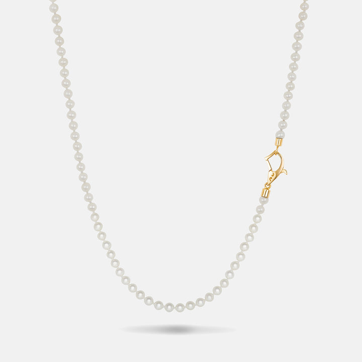 Beaded necklace in smooth white stones and a side-oriented yellow gold closure resting on a soft neutral background.
