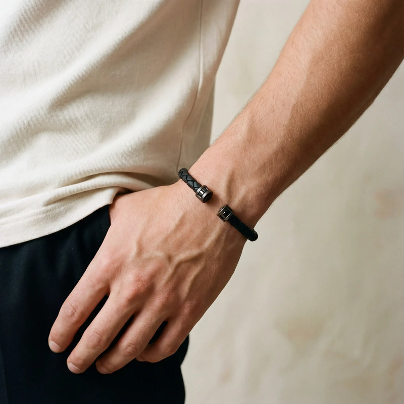 Close-up of a model wearing the Acies leather cuff, showing its black braided design and dark metal ends.