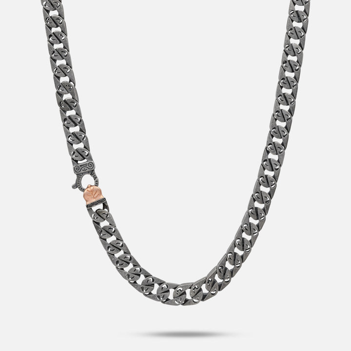 Heavy link necklace in oxidized silver and bronze against a stark white background.