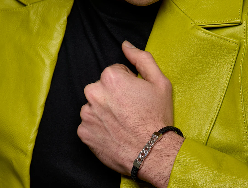 Close-up of a man wearing a black braided bracelet with a patterned metal detail.