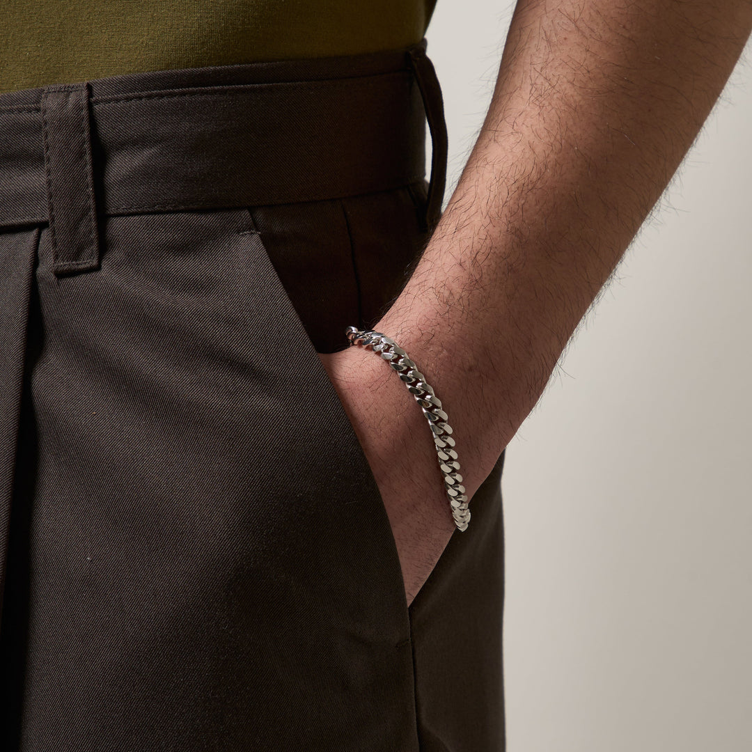 Close-up of a man wearing a silver-tone chain bracelet.