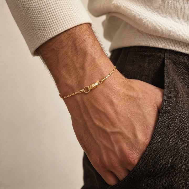 Male model wearing the Ulysses Slim Tubular Bracelet in polished yellow gold vermeil, featuring a delicate chain and clasp detail.