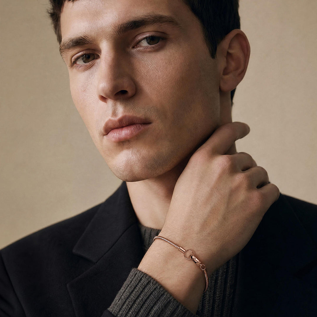 Close-up of a male model wearing the Ulysses Slimline bracelet in 18K rose gold vermeil with a polished minimalist design
